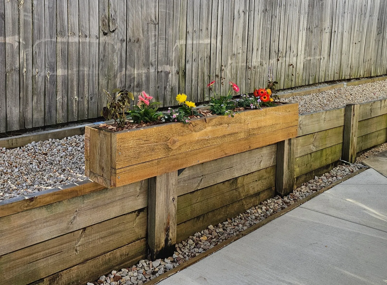 Timber retaining wall with built-in planter box and flowers