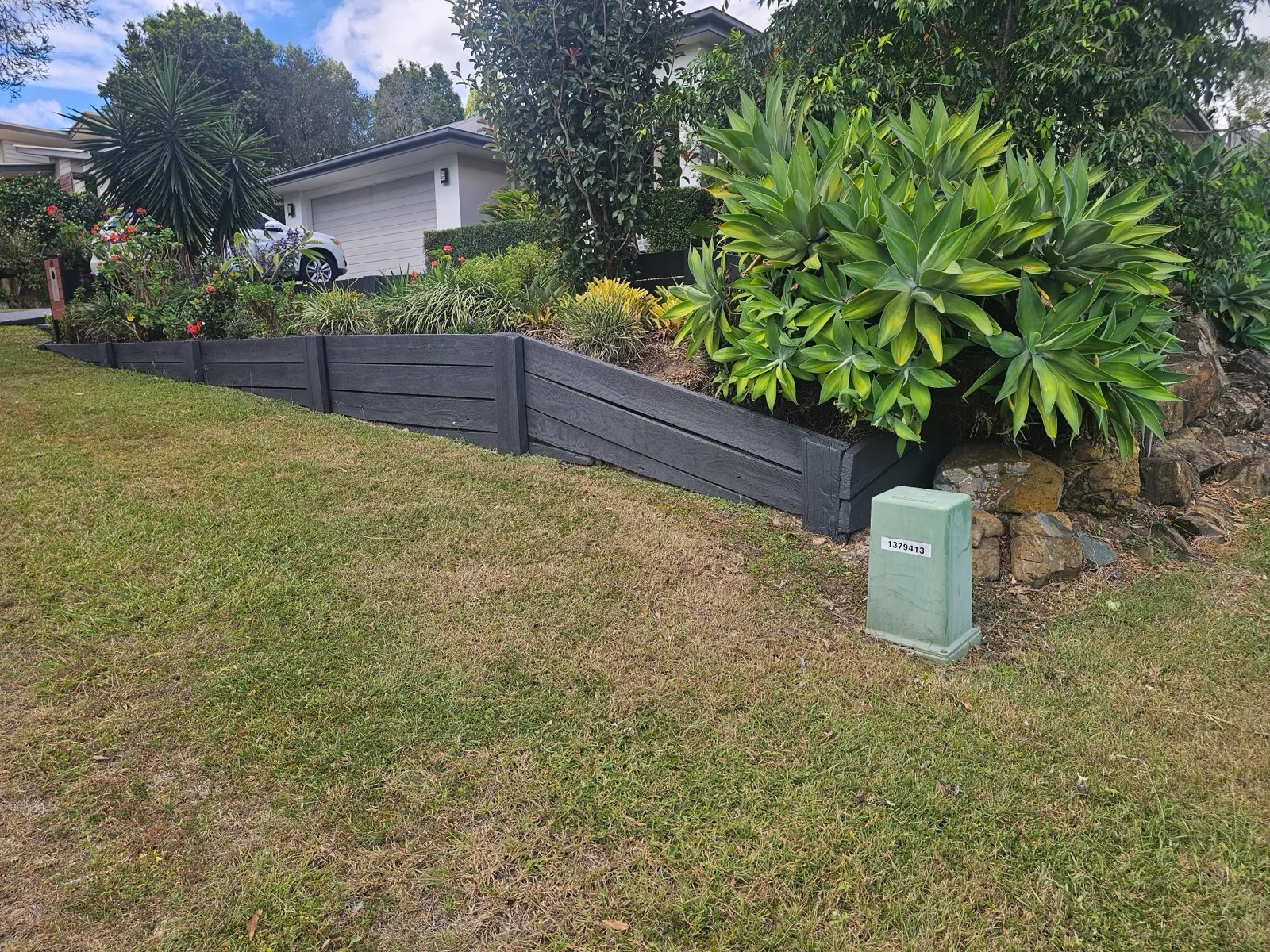 Timber sleeper retaining wall with landscaping — after